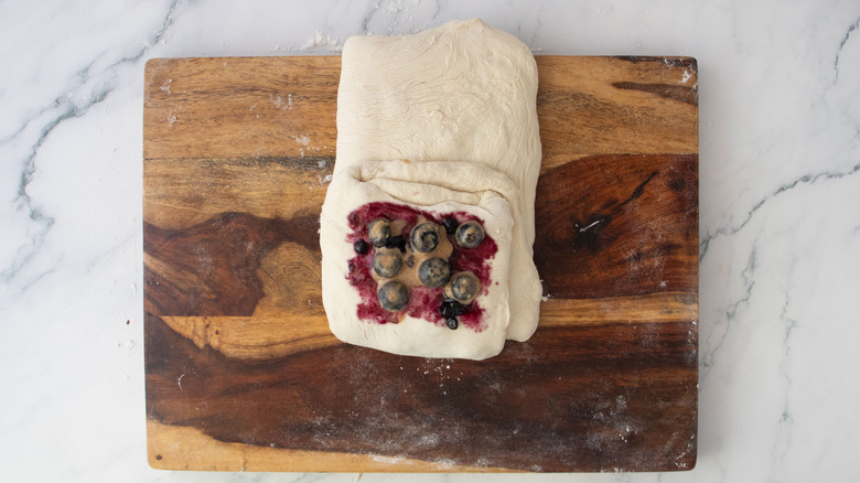 Folded dough with middle part topped with jam and spiced blueberries