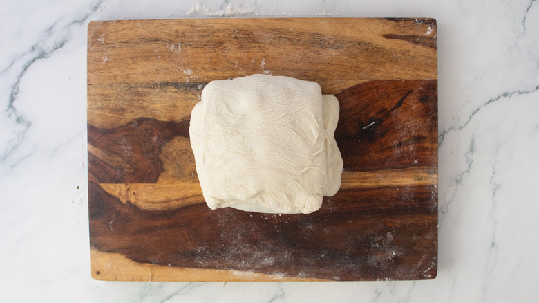 Folded over dough square on wooden board