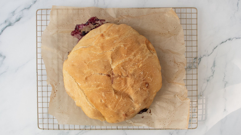 Baked bread boule on parchment paper on wire rack