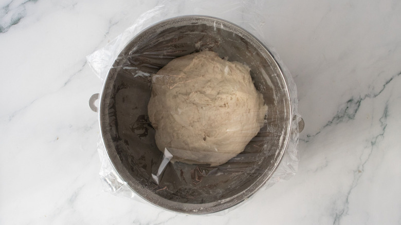 Dough in bowl covered with plastic