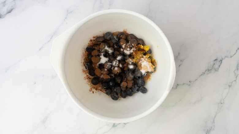 Blueberries, sugar, lemon zest, and spices in bowl