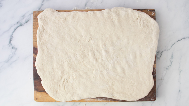 Stretched out dough rectangle on wooden board