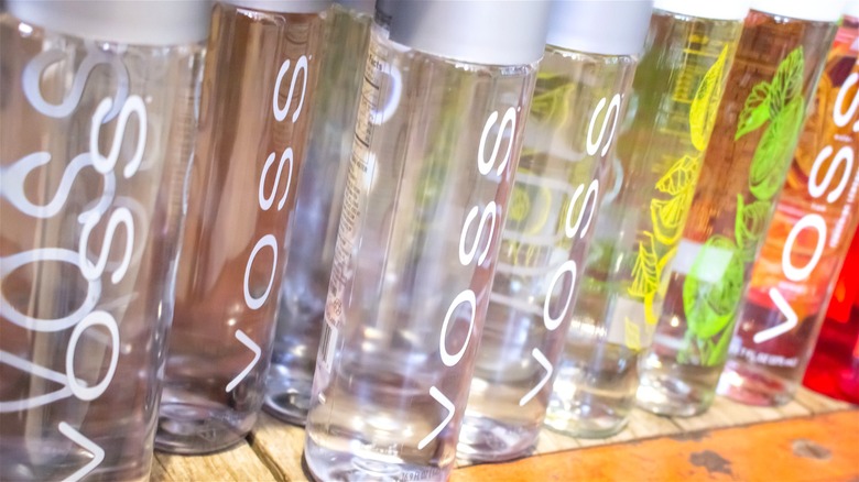Assorted Voss water products on a wooden grocery shelf.