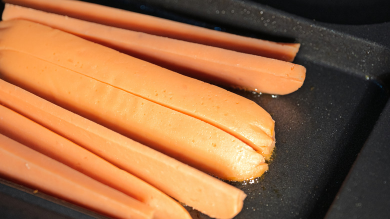Hot dogs on a griddle.