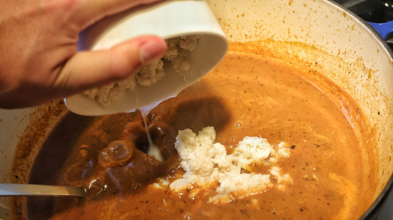 lump crab meat falling from bowl into pot of chilpachole