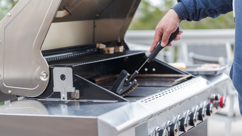 Man holding bristle brush while cleaning grill