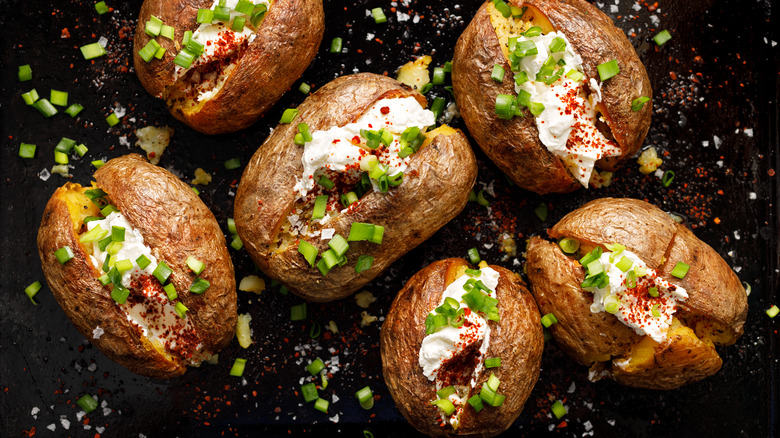 Loaded baked potatoes on black background