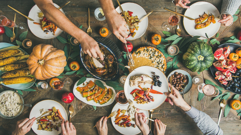 Thanksgiving table with turkey and sides, hands sharing