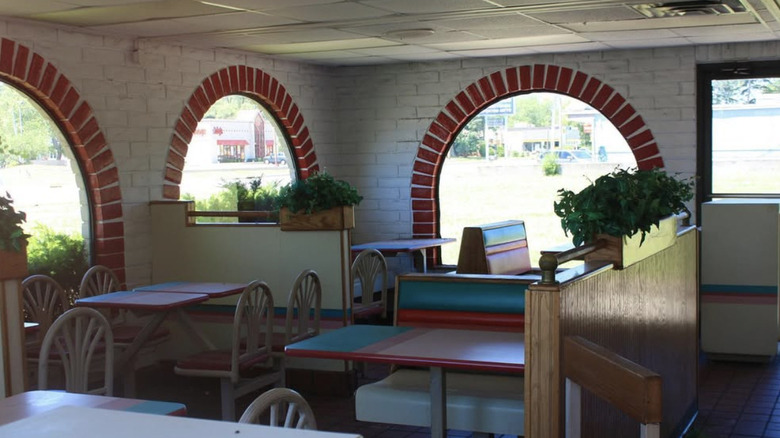 The inside of an old Taco Bell with striped tables and chairs.