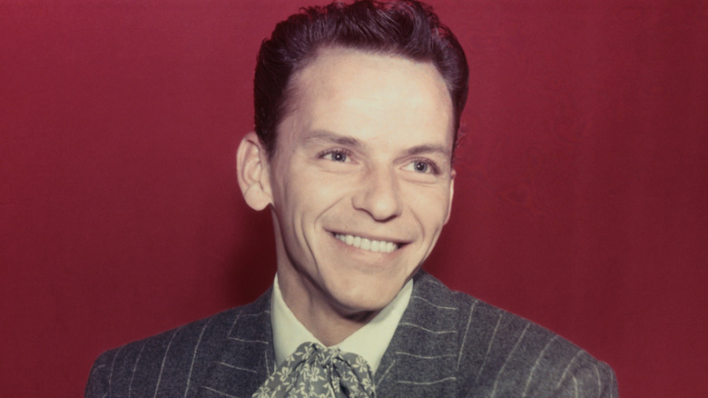Young Frank Sinatra smiling against a red background