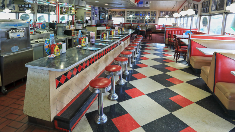Interior of classic diner with checked floors and red stools