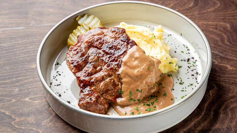 ground beef dish with gravy, potatoes, and pickles