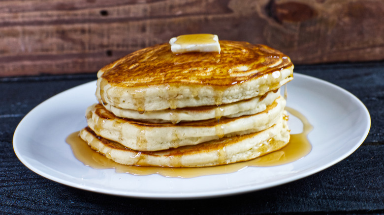 stack of pancakes with butter on white plate