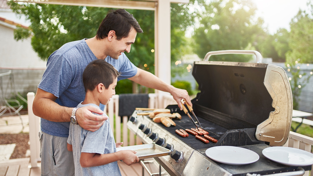 Child and adult grilling hot dogs together