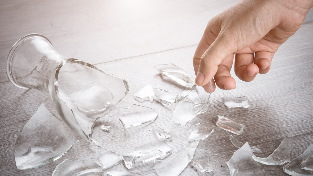 Hand picking up broken glass