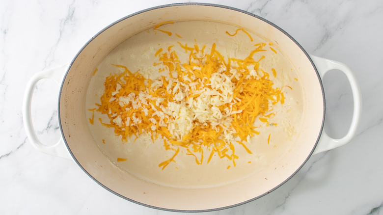 cream sauce in dutch oven with shredded cheese