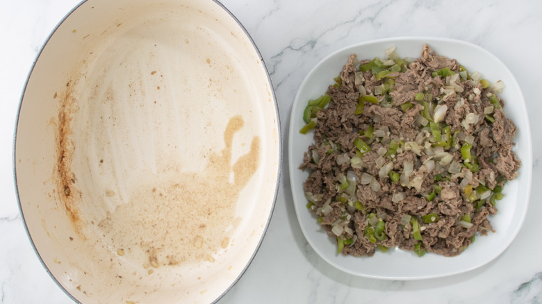 cooked meat and vegetables in plate next to dutch oven