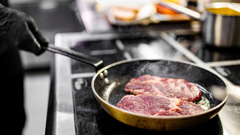 chef cooking steak in restaurant kitchen