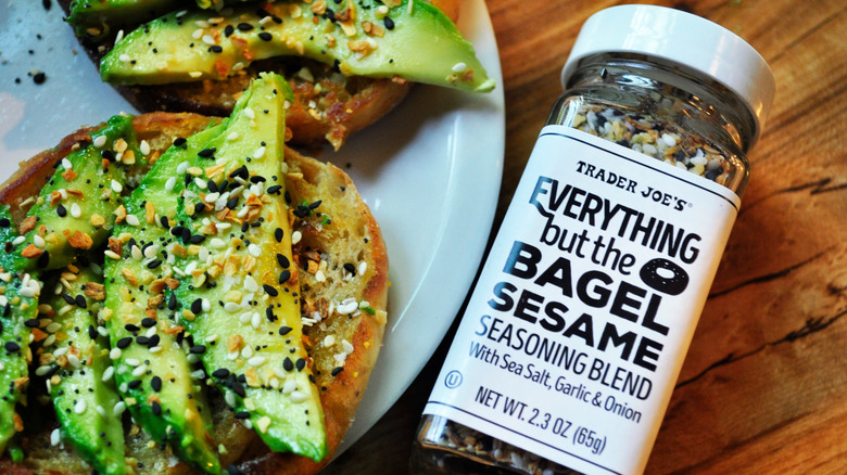 A bottle of Everything but the Bagel sesame seasoning blend sits next to seasoned avocado toast.