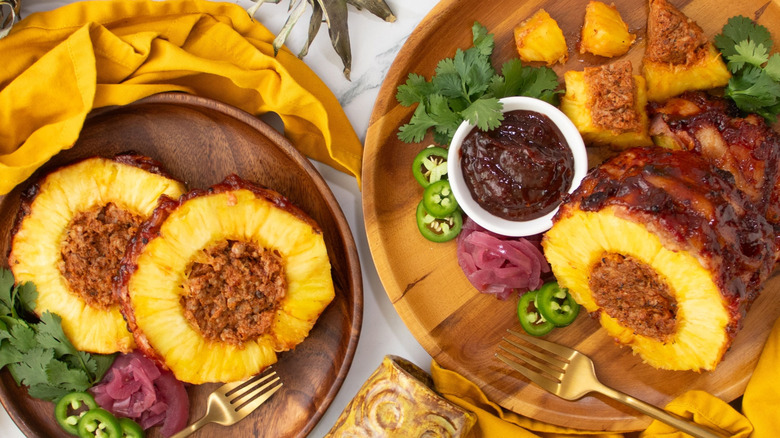 Pork-stuffed pineapple slices on plate next to stuffed pineapple with various toppings
