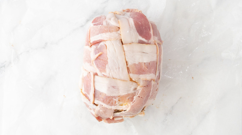 Raw bacon strips wrapped around pineapple