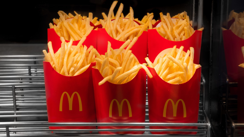 Cartons of McDonald's french fries under heat lamp in restaurant.