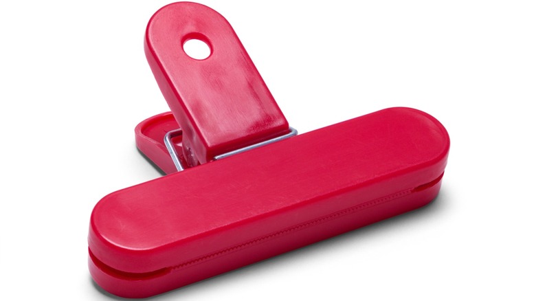 A red plastic bag clip against a white background.