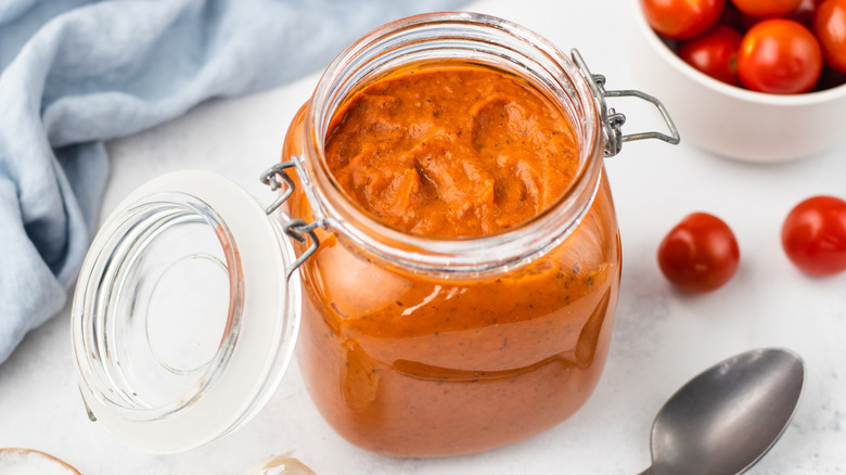 Jar of marinara sauce next to bowl of fresh cherry tomatoes