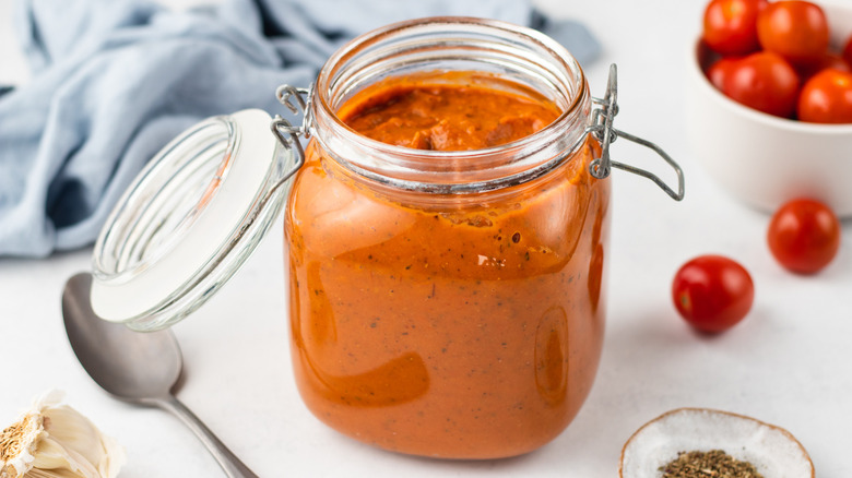 Jar of marinara sauce next to bowl of cherry tomatoes