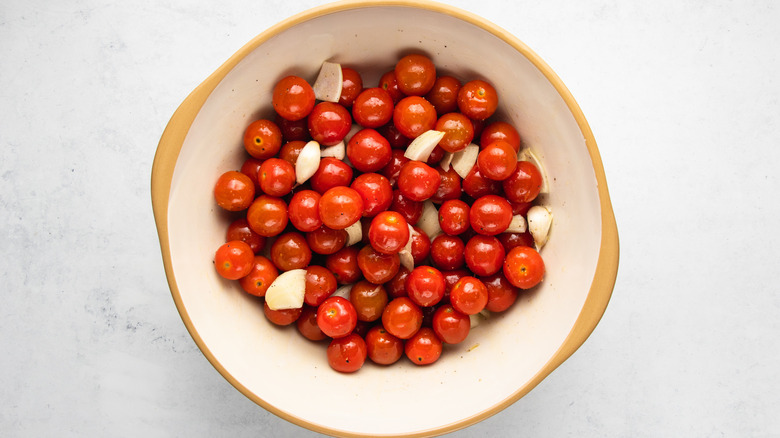 Cherry tomatoes, diced onion, and garlic tossed with oil in mixing bowl