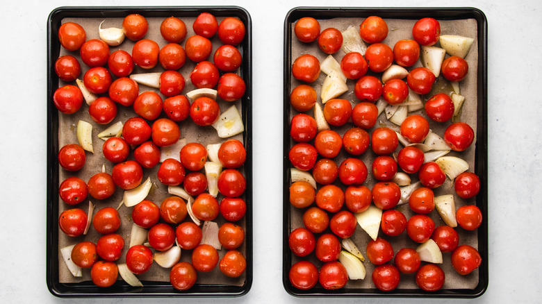 Cherry tomatoes, diced onion, and garlic cloves on two baking sheets