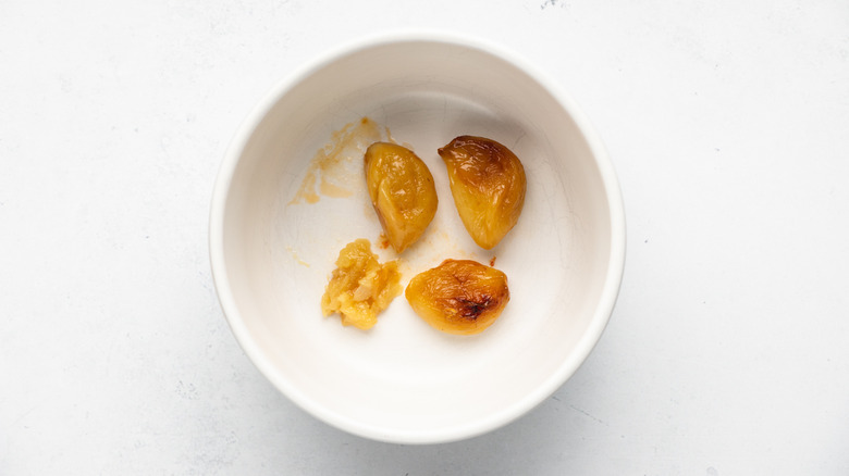 Peeled roasted garlic cloves in small white bowl