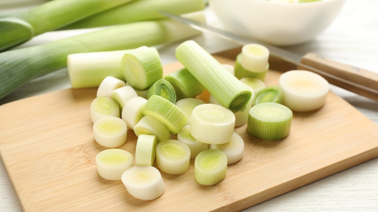 Sliced up leeks on a cutting board with a knife