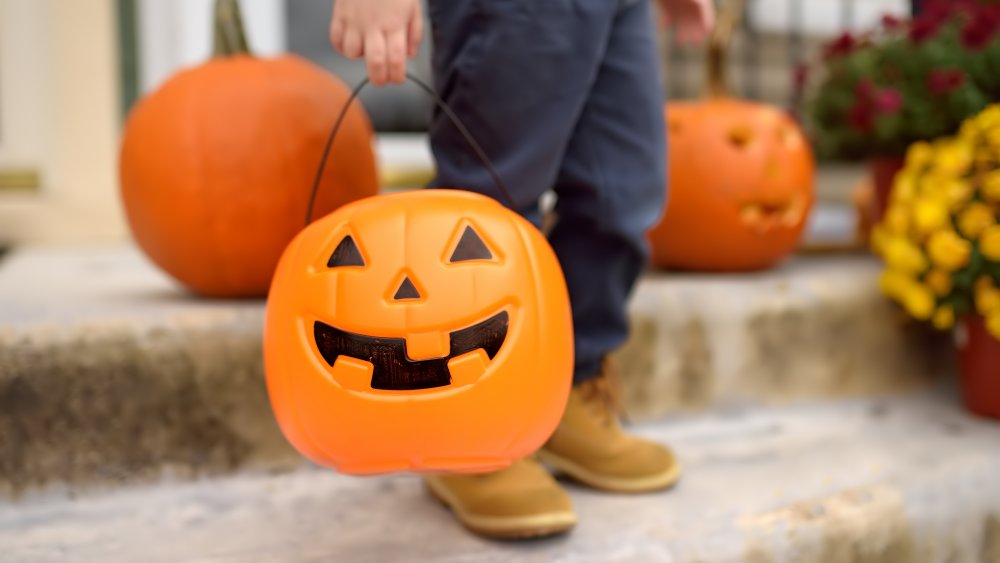 child on steps with a Halloween pumpkin bucket