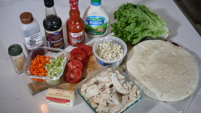 Buffalo chicken wrap ingredients laid out on a cutting board