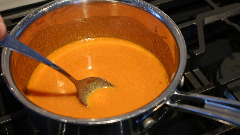 small saucepan of Buffalo sauce with spoon in it