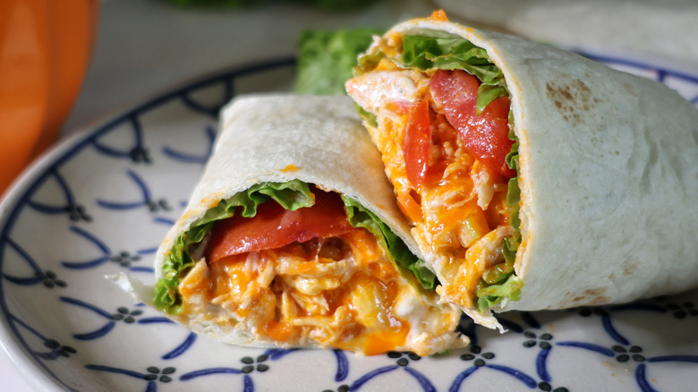 sliced, plated Buffalo chicken wrap with lettuce and tomato
