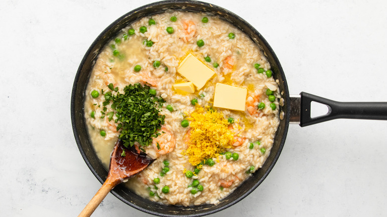 Adding butter, parsley, and lemon zest to pan of risotto