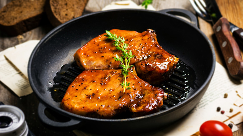 Cooked pork chops in cast iron pan.