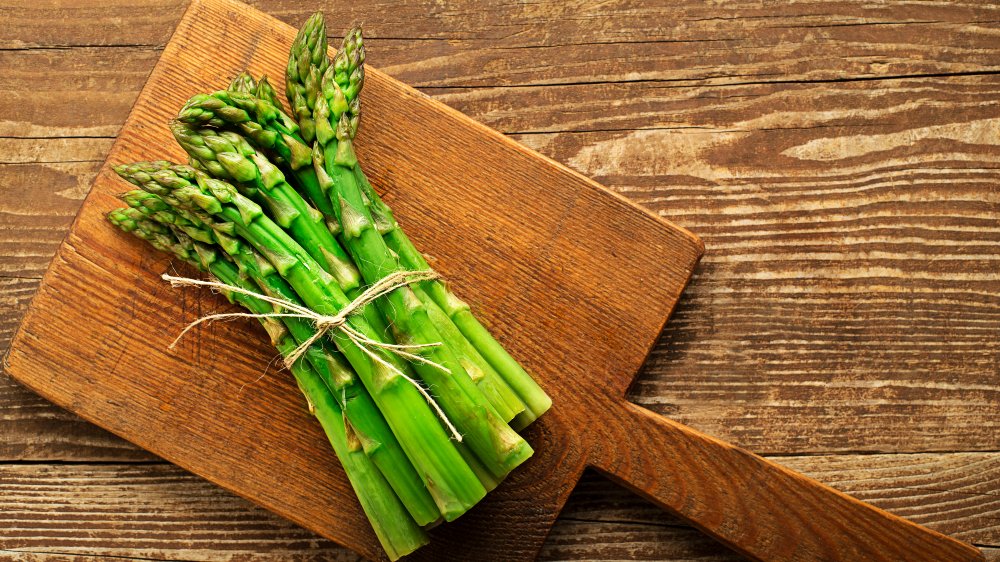 bunch of asparagus on wood cutting board