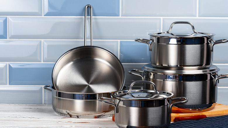 Silver pots and pans against tiled wall