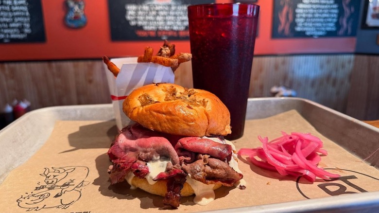 Barbecue beef sandwich with soda, fries, and pickled red onions