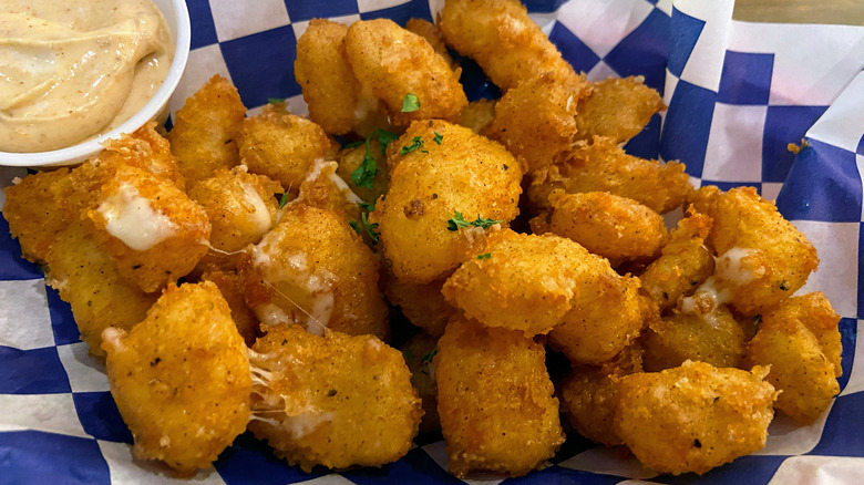 Fried cheese curds and sauce on blue checked paper