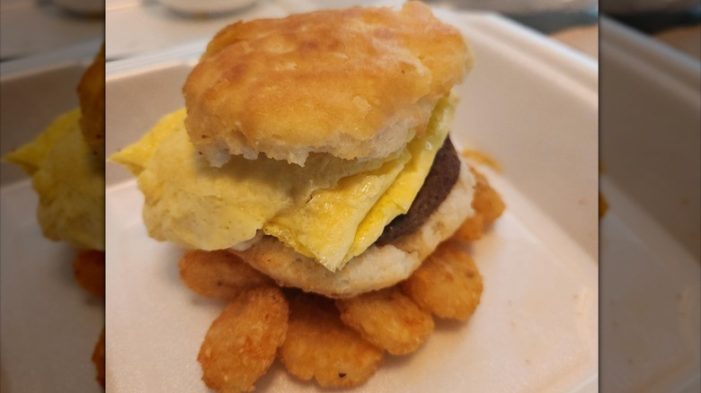 A Hardee's breakfast sandwich on biscuit with hash brown bites