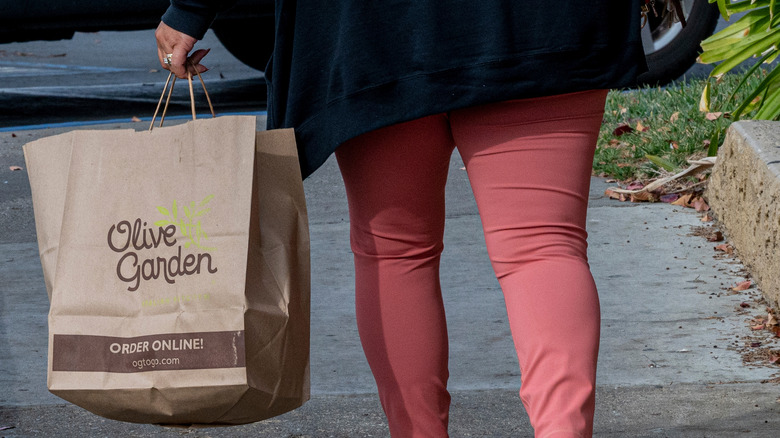 Woman carrying Olive Garden takeout bag