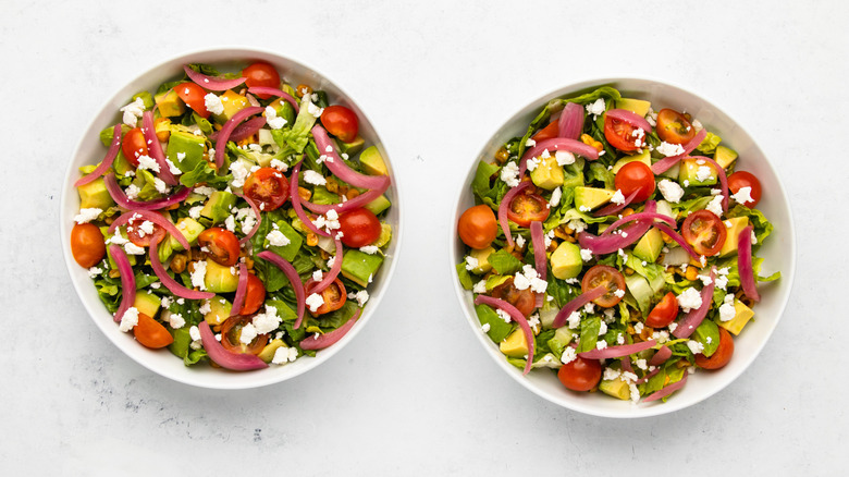 Two bowls of salad with crumbled cotija cheese