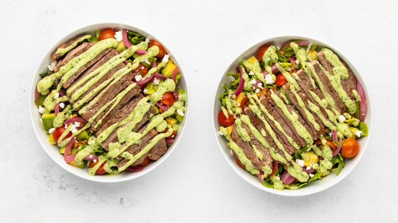 Two bowls of steak taco salad with avocado dressing