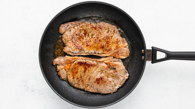 Two sirloin steaks cooking in frying pan
