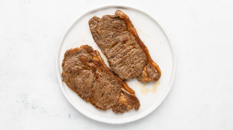 Two cooked sirloin steaks resting on a plate