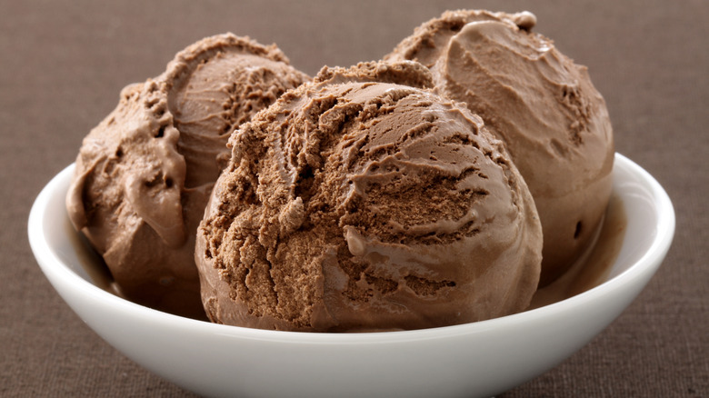 Closeup of chocolate ice cream in a white bowl on a brown background